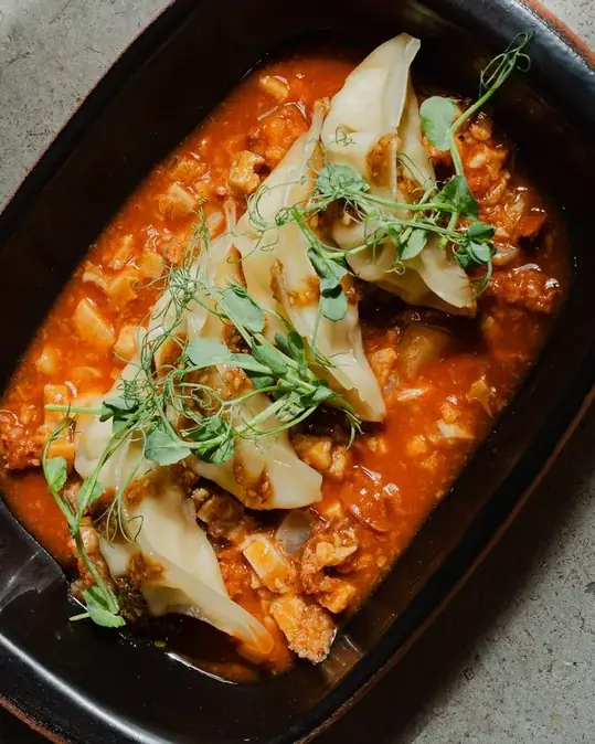 Gyozas de gamba en su cazuela, con brotes por encima